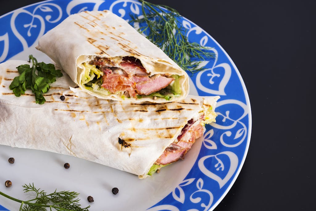 Delicious grilled chicken wrap with fresh vegetables served on a colorful plate.